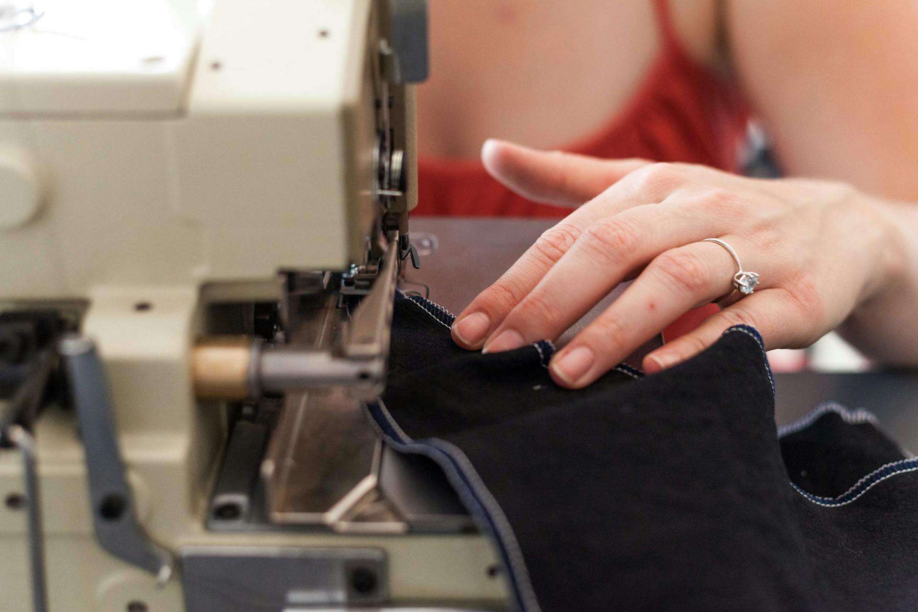 a person wearing a diamond ring using a sewing machine